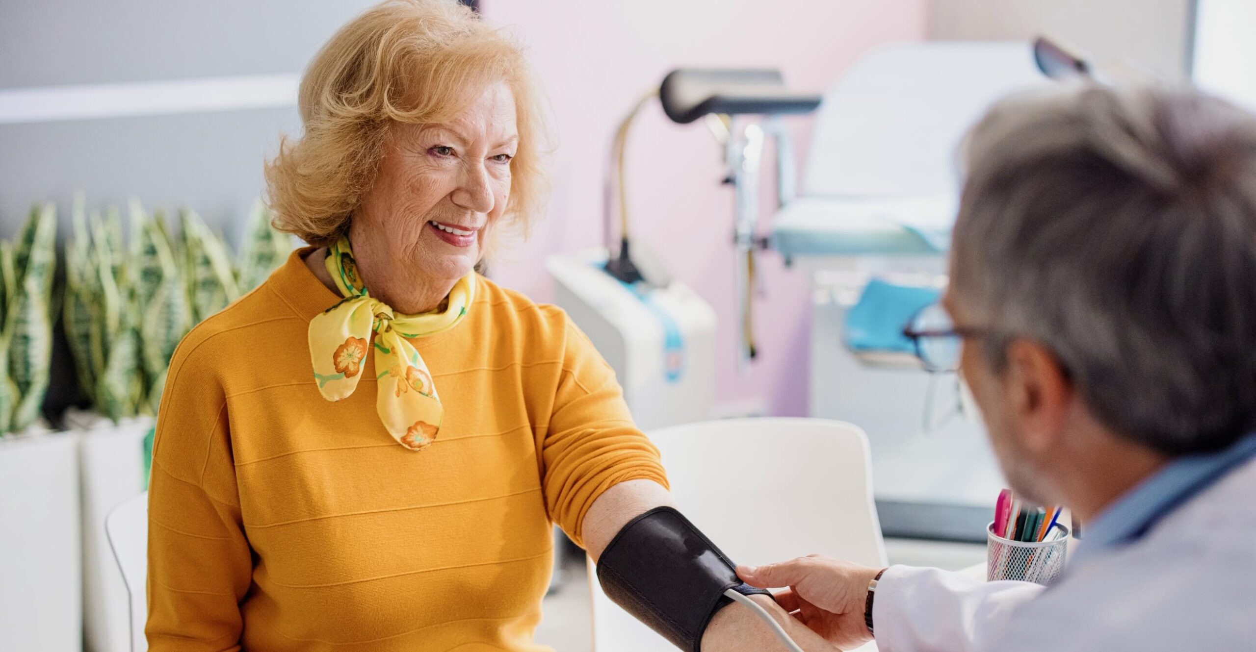  Doctor checking female patient's blood pressure in clinic 