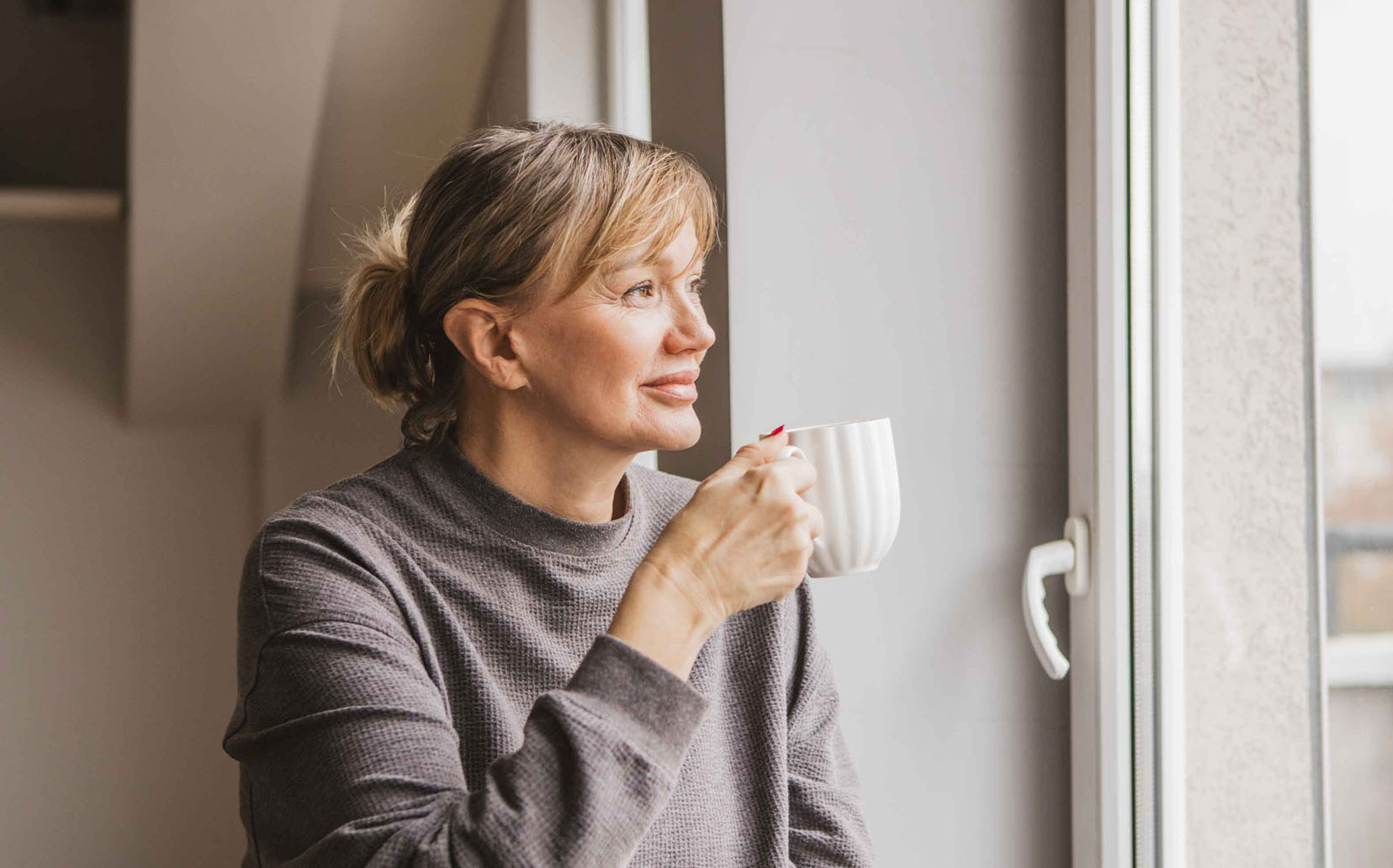 Woman looking thoughtful out window while sitting indoors